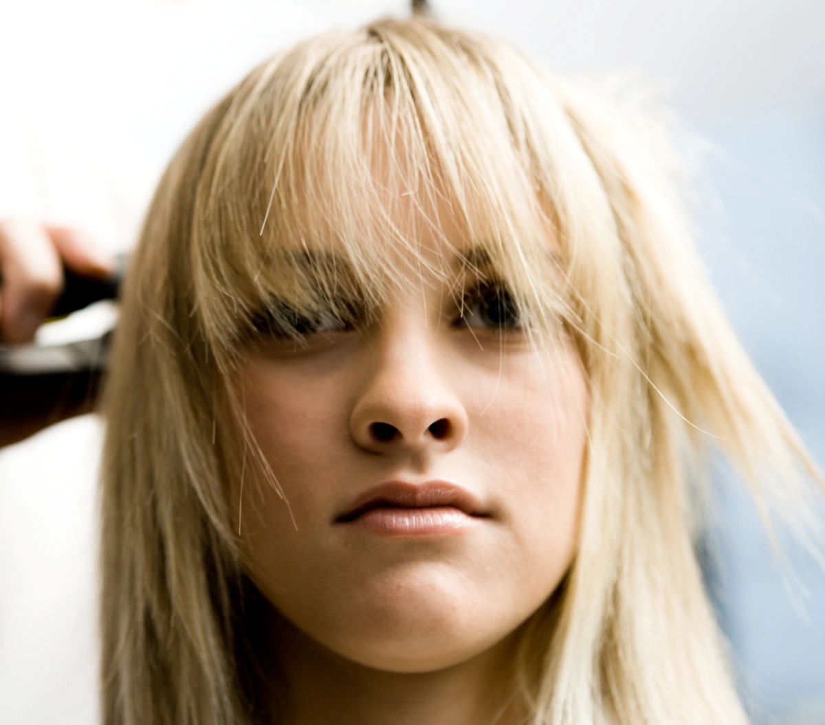 A blonde straightens her hair at the hairdresser's